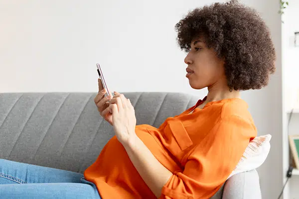 pregnant woman thinking about the benefits of open adoption while looking on her phone